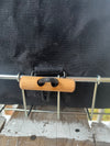 Close-up of a black fabric bag or basket with a metal wire rack and a small wooden handle secured by a black strap.